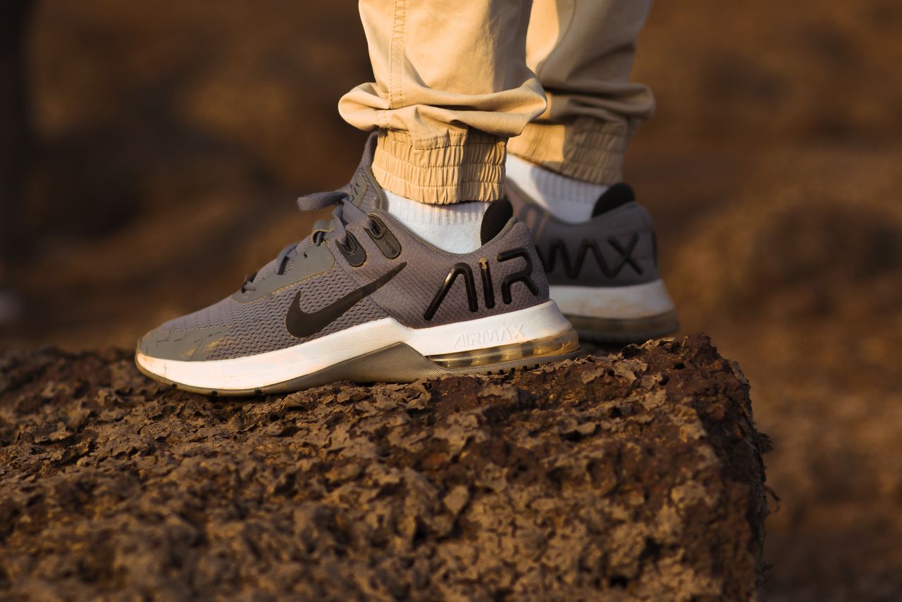 Close-up of athletic sneakers worn atop a rocky surface outdoors at sunset.